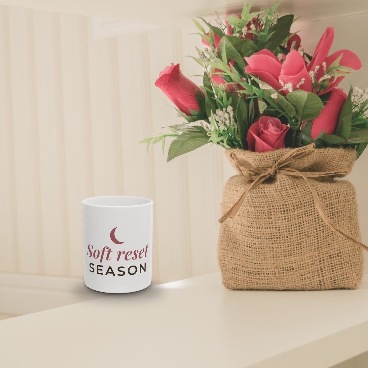 Soft Reset Season mug on a shelf beside flowers