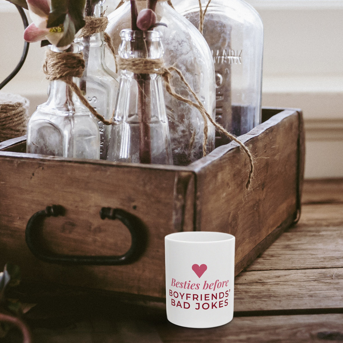 Besties Before Boyfriends Bad Jokes mug beside a rustic wooden crate of glass bottles